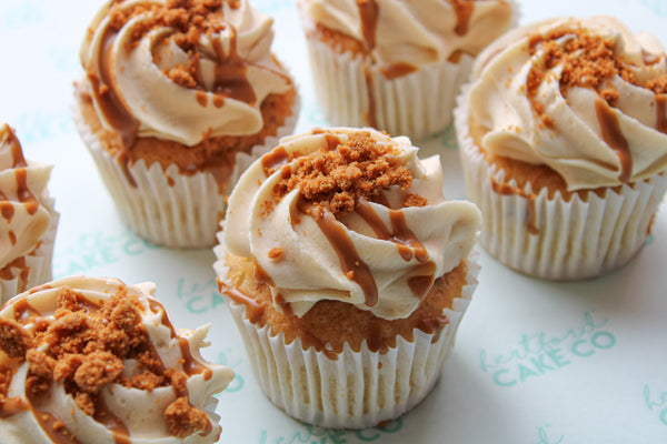 A photo of several Biscoff cupcakes with buttercream frosting and a sprinkle of Biscoff crumb on top, set on a light background.