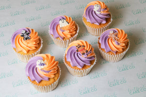 Halloween character cupcakes with vanilla sponge, purple and orange buttercream swirls and spooky ghost and skeleton decorations.